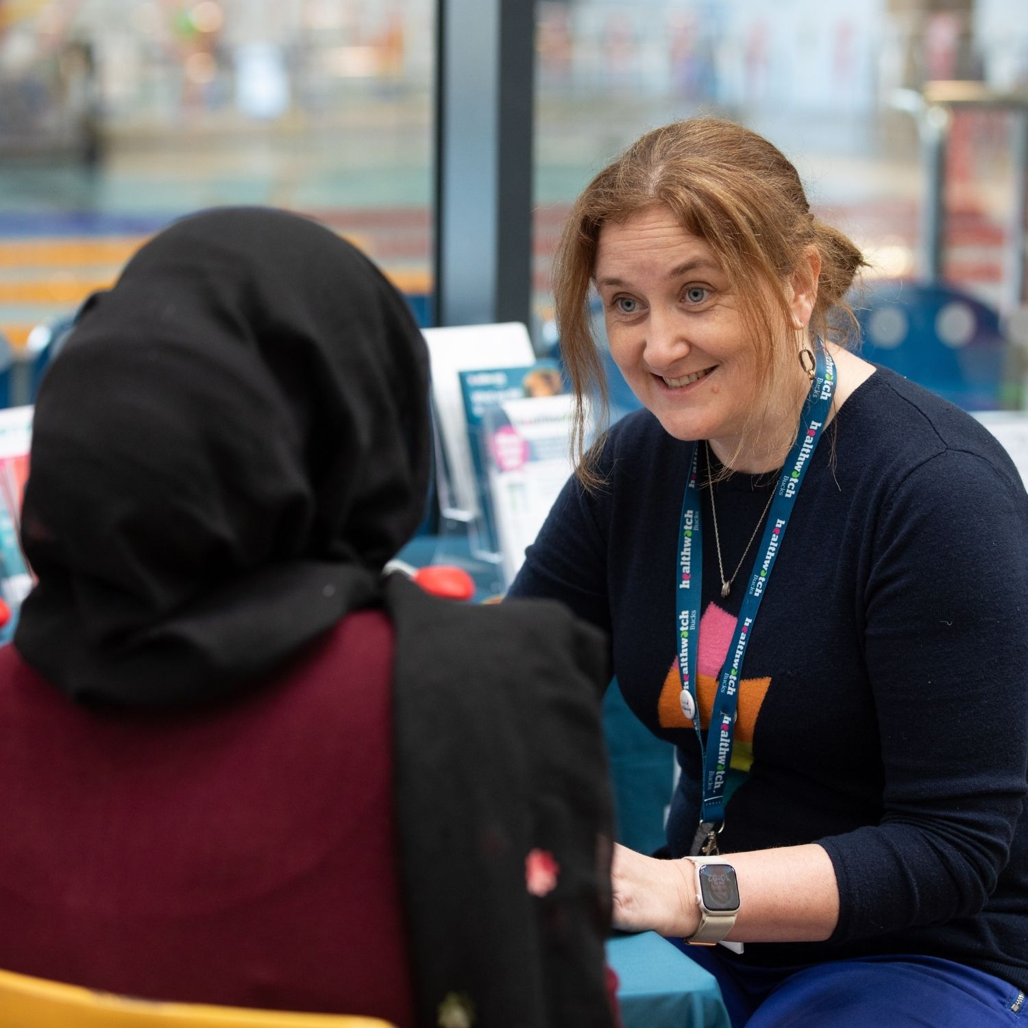 A picture of a female Healthwatch Engagement Officer sat down and chatting to a woman.